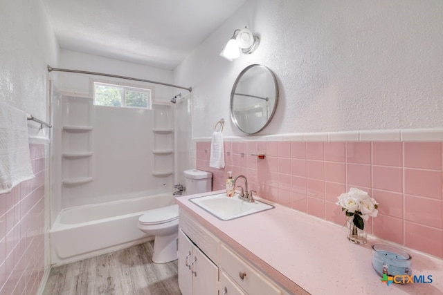 full bathroom with shower / bath combination, wood-type flooring, toilet, vanity, and tile walls