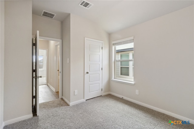 unfurnished bedroom with light colored carpet, vaulted ceiling, and a closet