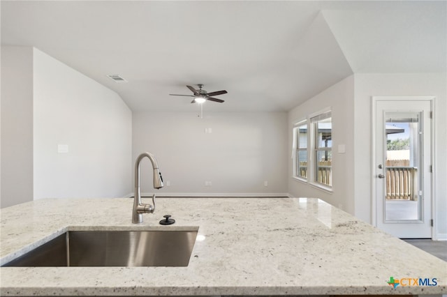 kitchen with light stone countertops, sink, and ceiling fan