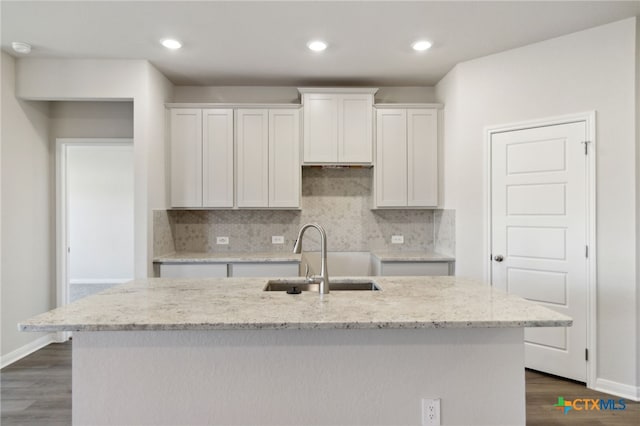 kitchen with white cabinetry, sink, dark hardwood / wood-style floors, backsplash, and an island with sink