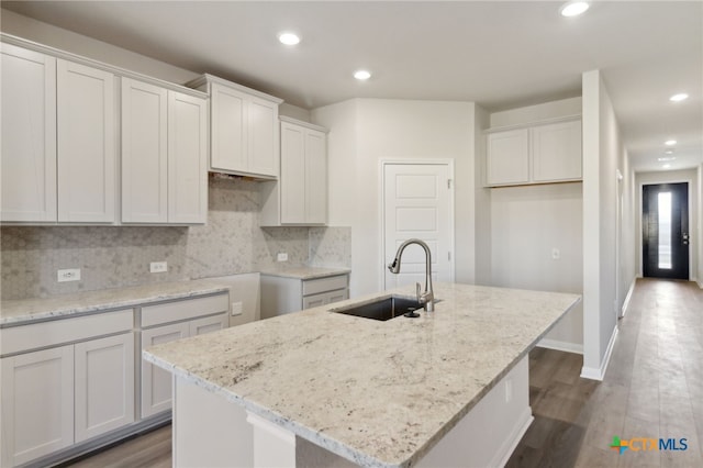 kitchen with white cabinetry, sink, and a kitchen island with sink