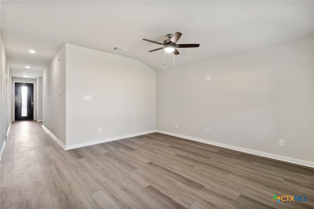 empty room with ceiling fan, vaulted ceiling, and light hardwood / wood-style flooring