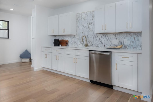kitchen featuring dishwasher, a sink, light countertops, light wood finished floors, and decorative backsplash