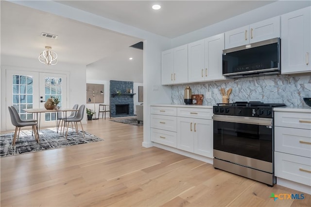 kitchen featuring stainless steel appliances, backsplash, white cabinetry, light wood-type flooring, and recessed lighting