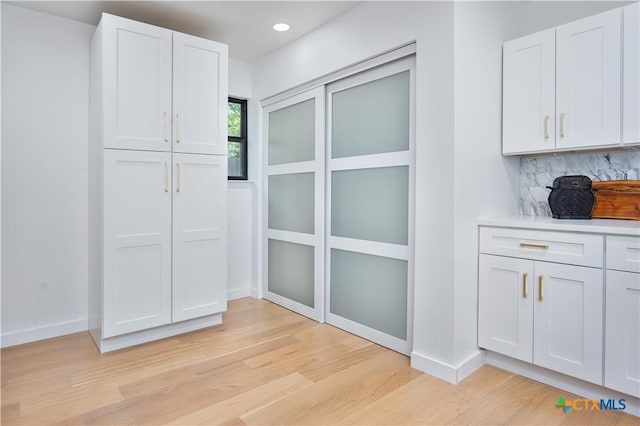 detailed view of wood finished floors, baseboards, backsplash, and recessed lighting