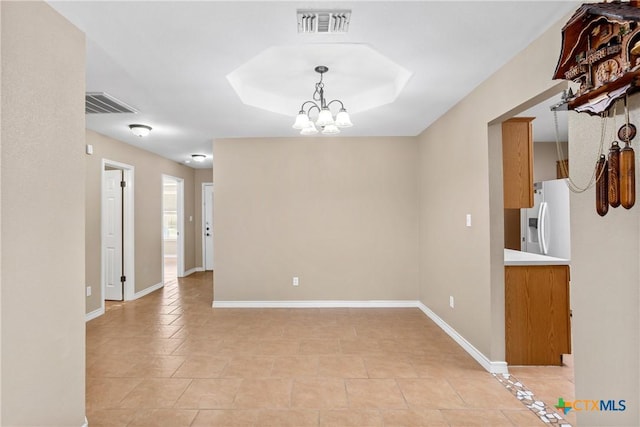 empty room with light tile patterned flooring, a notable chandelier, visible vents, and baseboards