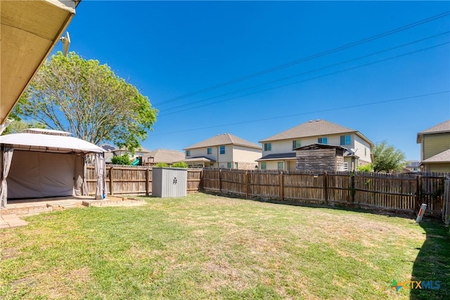 view of yard featuring a gazebo, a fenced backyard, and a residential view