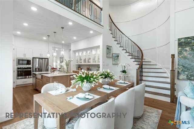 221 Dycus Bnd, Liberty Hill, TX 78642 - dining area with stairs, wood finished floors, a towering ceiling, and recessed lighting
