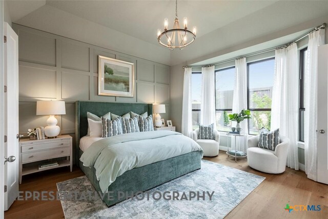 221 Dycus Bnd, Liberty Hill, TX 78642 - bedroom featuring a chandelier, wood finished floors, and a decorative wall