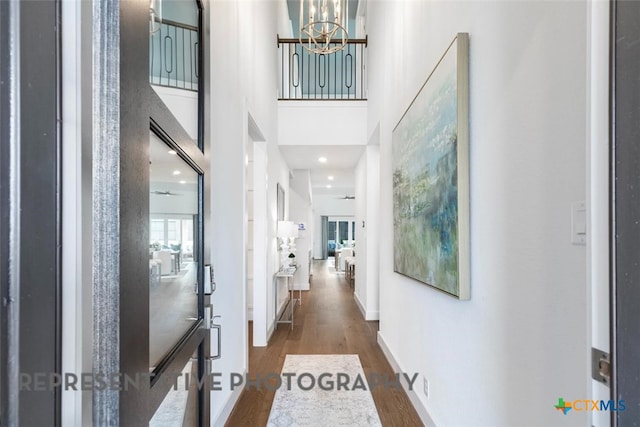 221 Dycus Bnd, Liberty Hill, TX 78642 - hallway featuring wood finished floors, a chandelier, and a high ceiling