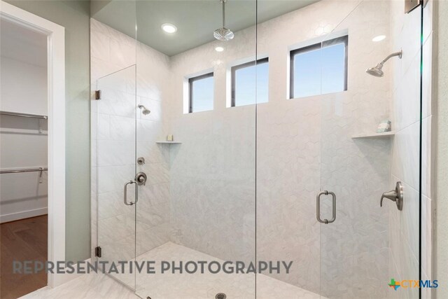 221 Dycus Bnd, Liberty Hill, TX 78642 - full bathroom featuring a stall shower, a spacious closet, and wood finished floors