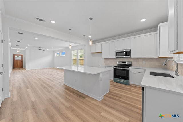 kitchen featuring white cabinets, appliances with stainless steel finishes, sink, and a center island