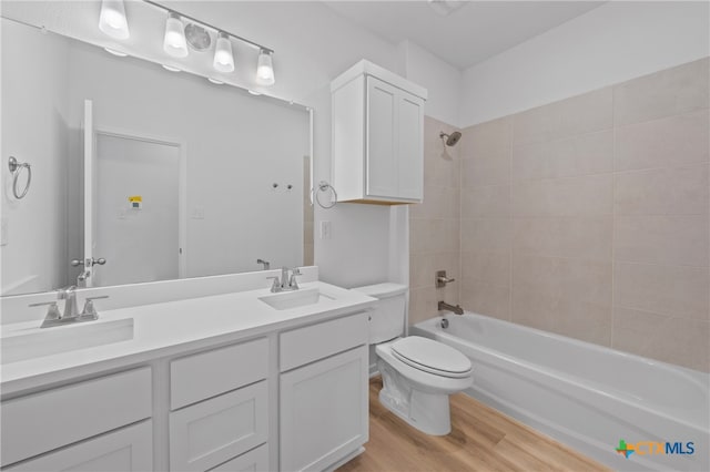 full bathroom with toilet, tiled shower / bath combo, vanity, and hardwood / wood-style flooring