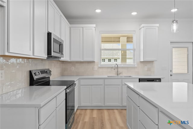 kitchen featuring white cabinets, sink, ornamental molding, pendant lighting, and appliances with stainless steel finishes