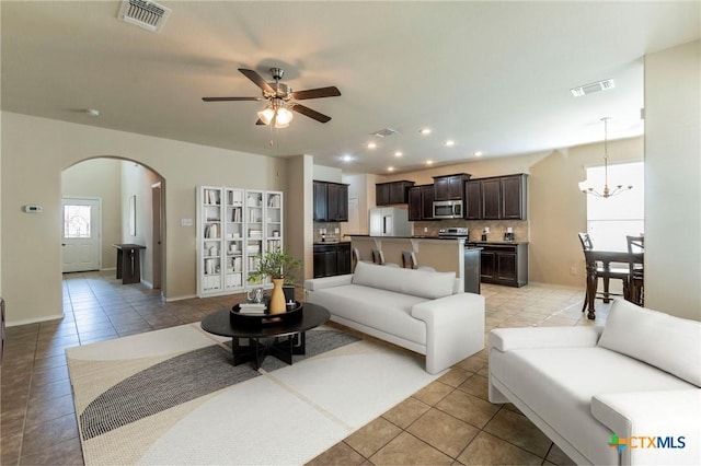 living room with light tile patterned floors and ceiling fan with notable chandelier