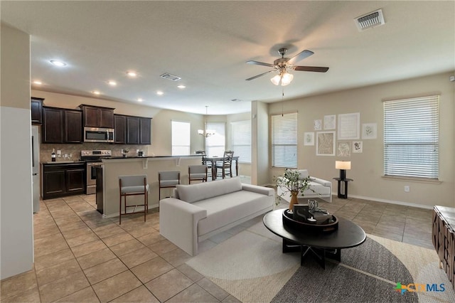 living room featuring ceiling fan with notable chandelier and light tile patterned floors