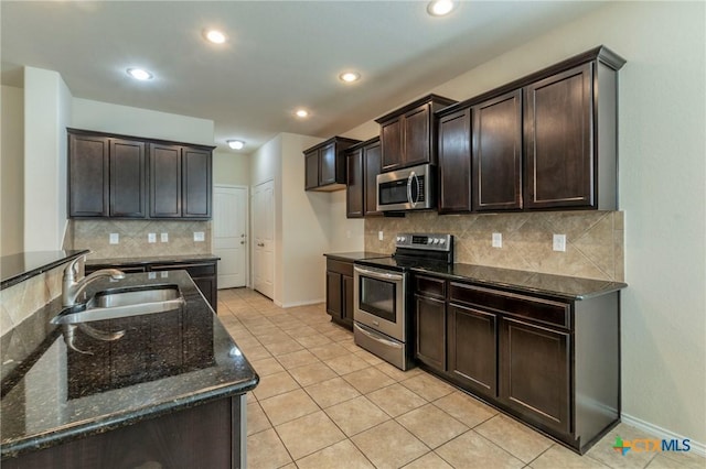 kitchen with dark stone counters, dark brown cabinets, stainless steel appliances, sink, and light tile patterned flooring