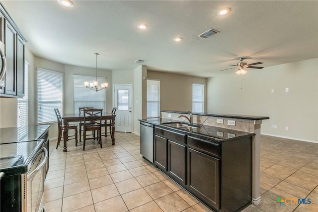 kitchen with ceiling fan with notable chandelier, stainless steel appliances, sink, hanging light fixtures, and an island with sink