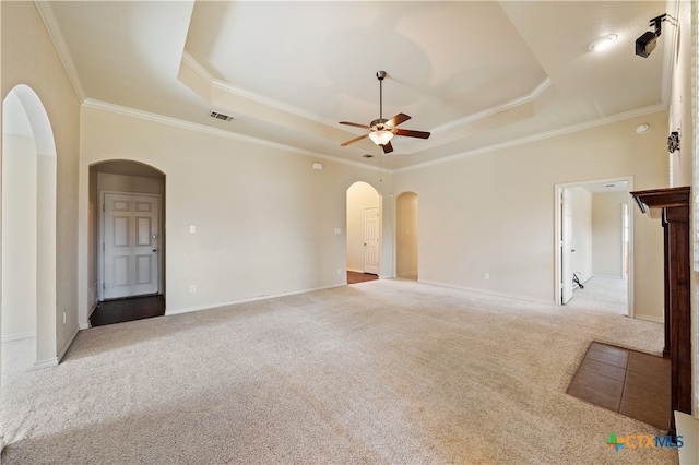 carpeted spare room with ceiling fan, crown molding, and a tray ceiling