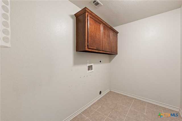 clothes washing area featuring washer hookup, electric dryer hookup, cabinets, and a textured ceiling