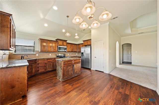 kitchen featuring dark hardwood / wood-style floors, tasteful backsplash, decorative light fixtures, a kitchen island, and stainless steel appliances