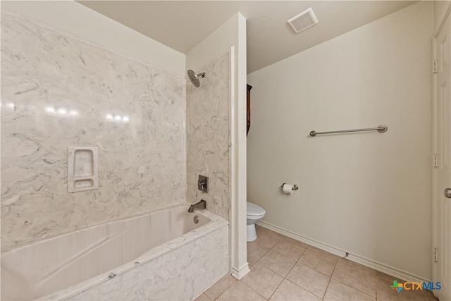 bathroom with tile patterned flooring, tiled shower / bath combo, and toilet