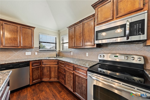 kitchen featuring light stone counters, stainless steel appliances, vaulted ceiling, dark wood-type flooring, and sink