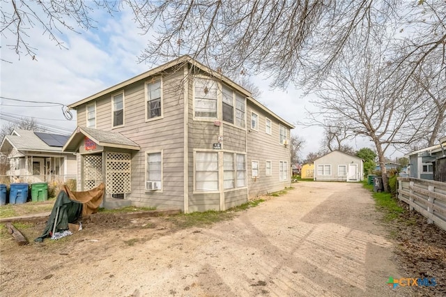 view of side of home featuring an outdoor structure, fence, and driveway