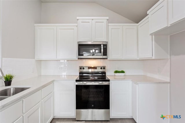 kitchen with white cabinets, lofted ceiling, and appliances with stainless steel finishes