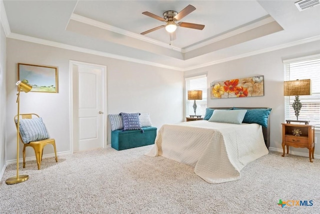 carpeted bedroom with a tray ceiling, ceiling fan, and ornamental molding