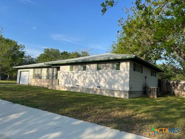 view of property exterior featuring a lawn, central AC unit, and crawl space