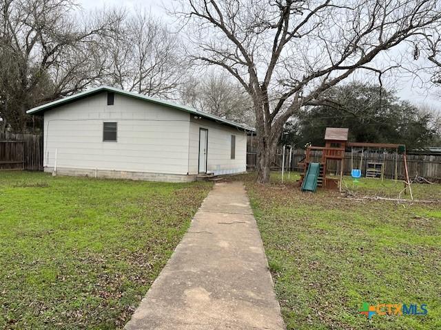 view of home's exterior with fence, a lawn, and a playground
