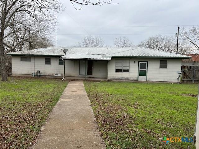ranch-style house with fence, a front yard, and metal roof