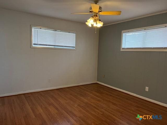spare room featuring baseboards, a ceiling fan, wood finished floors, and crown molding