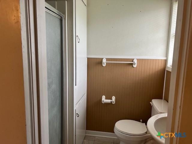 bathroom featuring wainscoting, a sink, a shower with shower door, and toilet