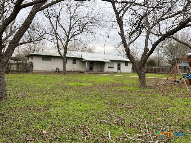 rear view of property with fence and a yard