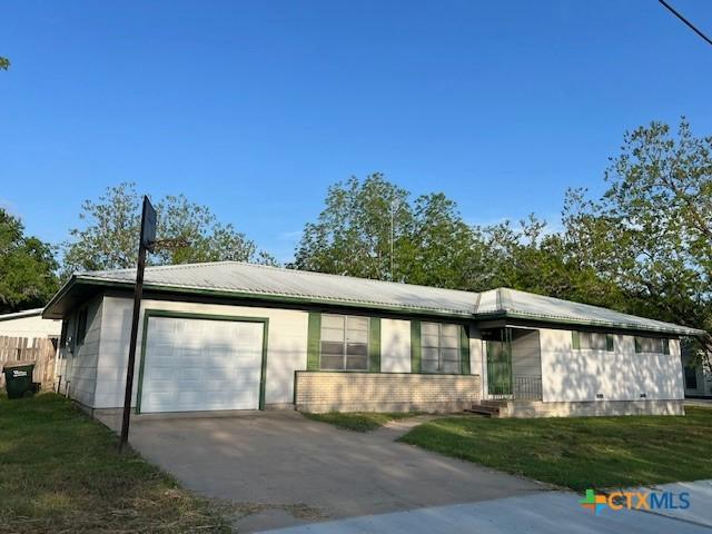 ranch-style home with an attached garage, driveway, and a front lawn