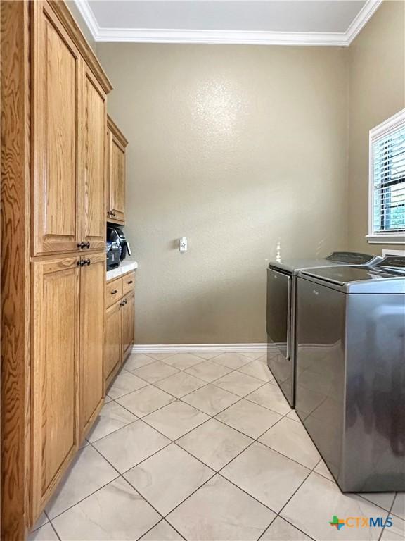 720 E Travis St, Luling, TX 78648 - laundry area with separate washer and dryer, ornamental molding, cabinet space, and light tile patterned flooring