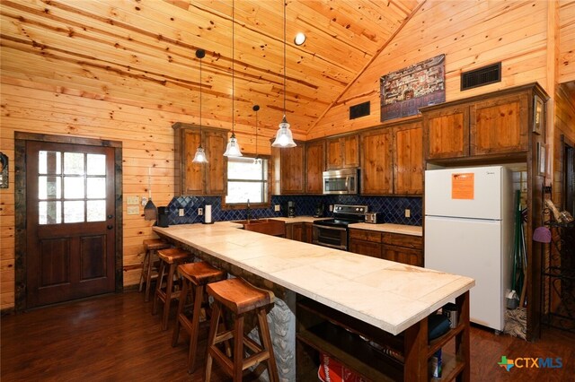 kitchen with high vaulted ceiling, wooden walls, plenty of natural light, and appliances with stainless steel finishes