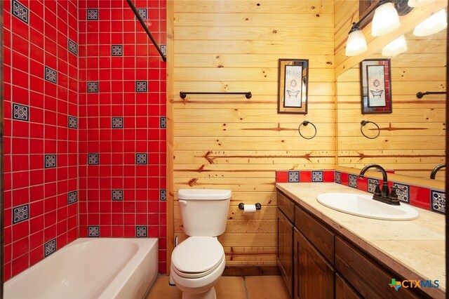 bathroom with a tub, vanity, wooden walls, and toilet