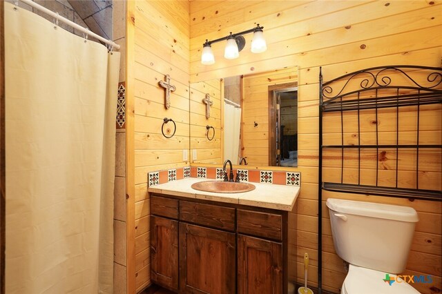 bathroom with toilet, vanity, wooden walls, and a shower with shower curtain