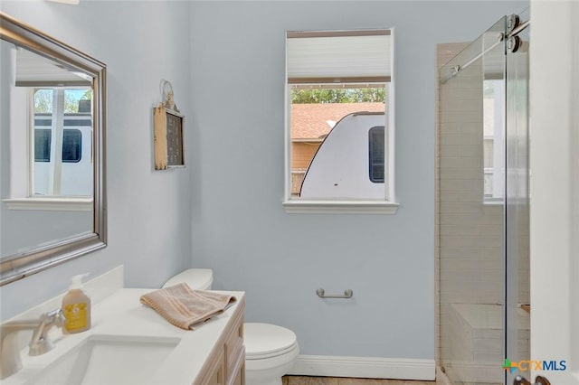 full bath featuring vanity, toilet, a shower with door, and baseboards