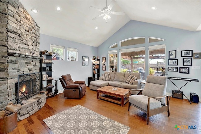 living area featuring high vaulted ceiling, a ceiling fan, a stone fireplace, wood finished floors, and recessed lighting