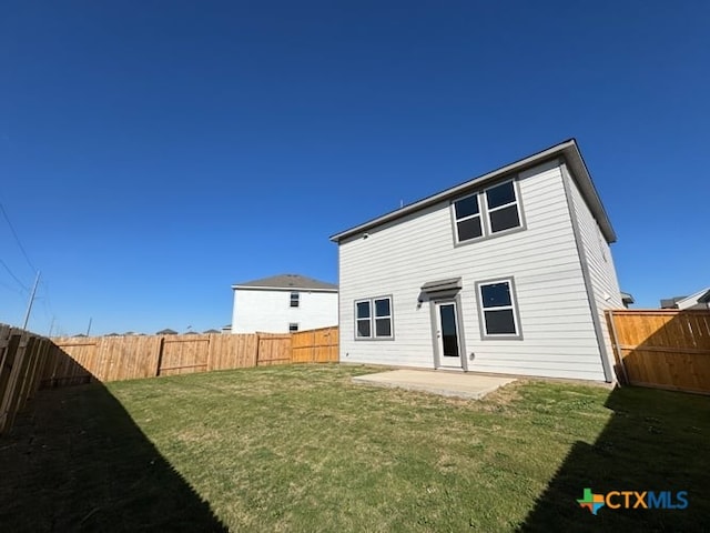 back of property with a yard, a fenced backyard, and a patio