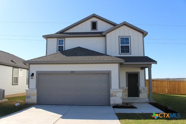 traditional-style home featuring fence, a shingled roof, an attached garage, board and batten siding, and driveway