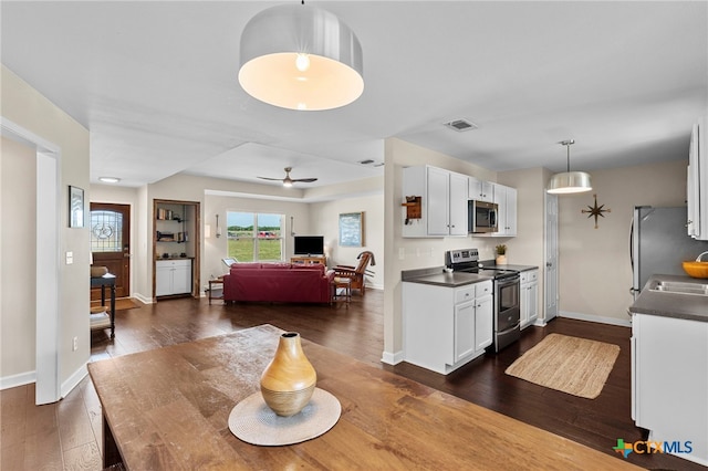 1975 Taylorsville Rd, Red Rock, TX 78662 - kitchen with dark countertops, ceiling fan, stainless steel appliances, white cabinetry, and dark wood-style floors