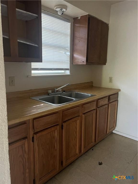410 Railroad St, San Marcos, TX 78666 - kitchen featuring open shelves, brown cabinetry, and light countertops