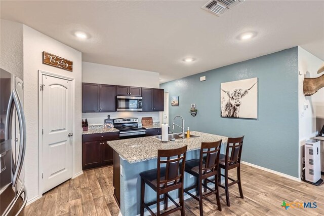 kitchen with visible vents, a kitchen bar, light wood-type flooring, appliances with stainless steel finishes, and a sink