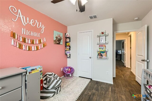 playroom with visible vents, a ceiling fan, baseboards, and dark wood-style flooring