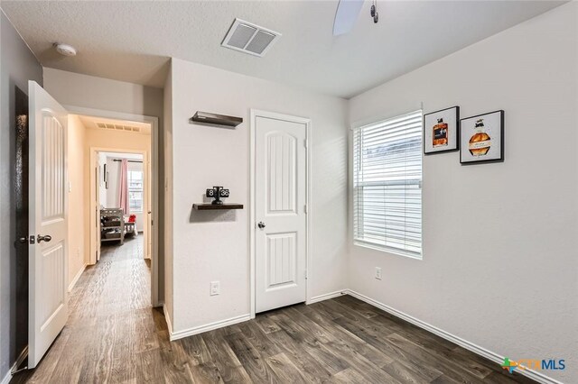 unfurnished bedroom with visible vents, baseboards, dark wood-type flooring, and a closet